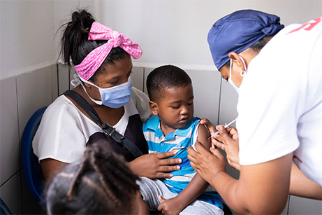 A health care worker gives a shot to a young boy