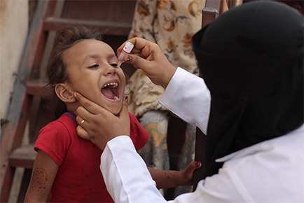 A boy is receiving medicine orally from a health care worker