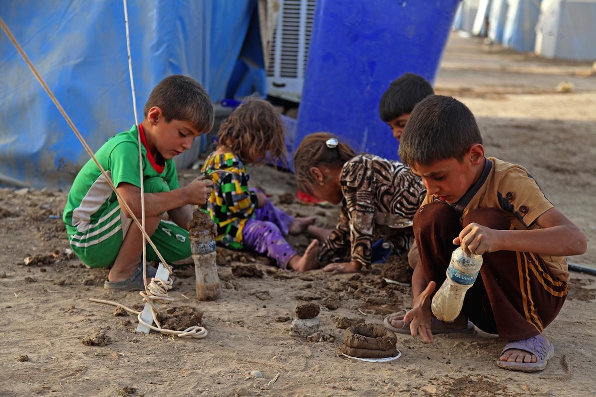 On 29 June 2014 in Iraq, children play in the dirt, outside a tent in the Khazar transit camp in the northern-eastern city of Erbil, capital of Kurdistan Region. 