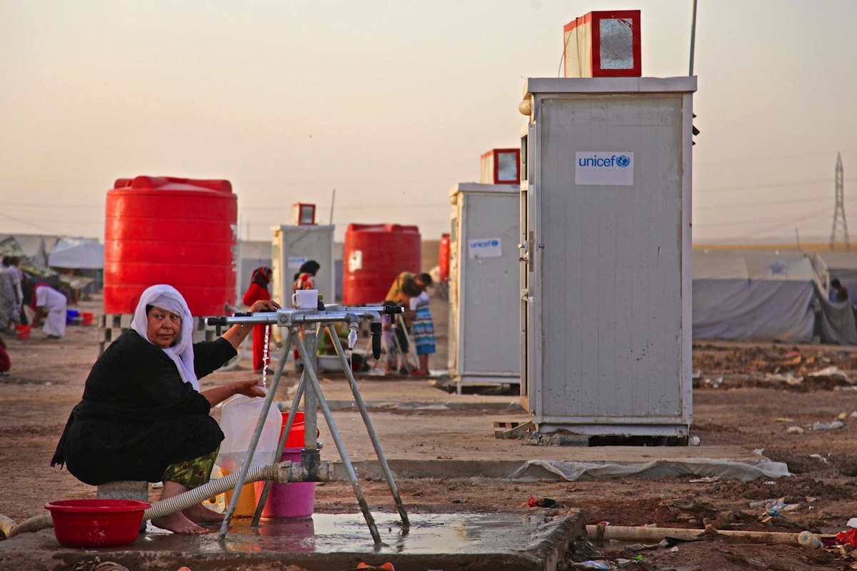 A displaced woman fills containers at a water point in the Khazar transit camp in the northern-eastern city of Erbil.