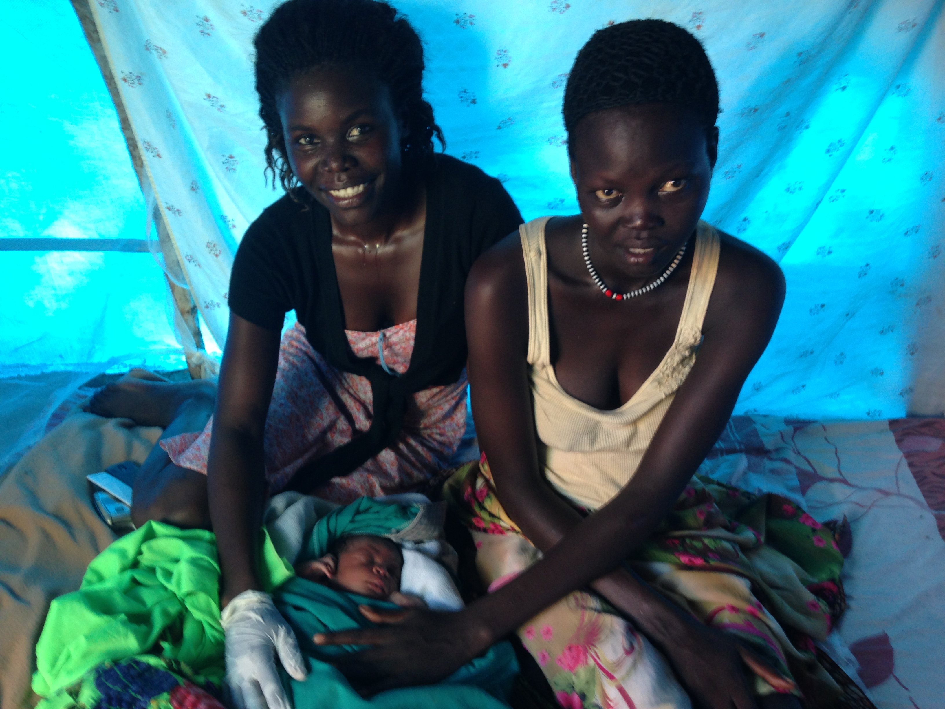 Florence (left) – a trained midwife – checks on the baby, and his mother Kuei, shortly after the baby’s birth. © UNICEF South Sudan/2014/KentPage