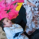A mother in a head scarf gazes at her child she is holding