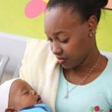 A mother holds a baby whom she looks lovingly at