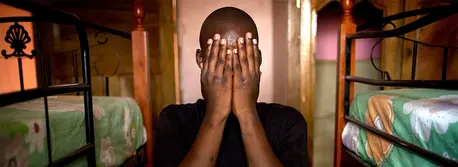 A boy covers his face after going through a trafficking ordeal. He waits to be reunited with his family at a safe place.