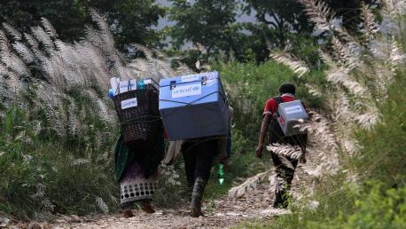Porters and a local health official carry UNICEF-provided vaccines across difficult terrain on their way to a health post in Barpak Village in Nepal's Gorkha district, the epicenter of the April 2021 earthquake. 