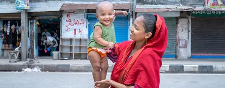 A mother holds her 8-month-old child in her neighborhood in Adabor, Bangladesh.