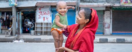A mother holds her 8-month-old child in her neighborhood in Adabor, Bangladesh.