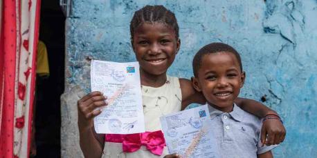 Merline, 12, and Koko, 9, proudly hold their birth certificates in front of their house in the commune of N'Sele in Kinshasa, DR Congo. They have benefited from catch-up birth registration through vaccination services - a project supported by the French Government.