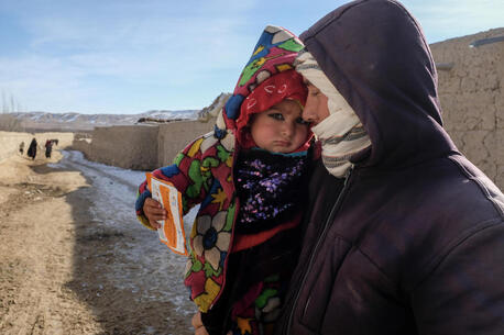 A father holds his daughter after she has received a checkup at a health center in Afghanistan.