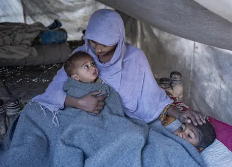 A mother keeps her children warm inside her tent after receiving a winter kit from UNICEF in the village of Zangi Brohy, Dadu District, Sindh Province, Pakistan.