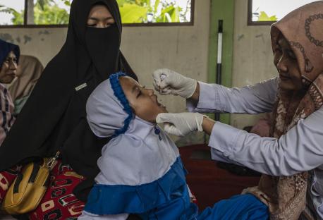 A mother sits with her daughter as she receives the polio vaccine at the Darul Zikri Islamic School during a polio immunization campaign in Aceh Tamiang Regency, Aceh Province, Indonesia.