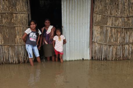 A woman and children stand in floodwaters in Primavera, a rural community located in Cura Mori District outside the city of Piura, Peru.