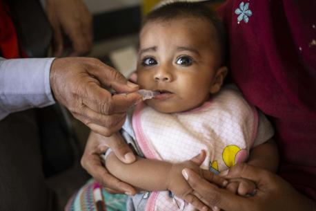 In Pakistan, a 6-month-old sits on his mother's lap while getting his second dose of the rotavirus vaccine