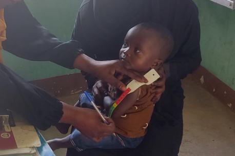 On May 1, 2023, a nutrition assistant screens a child for malnutrition using a Mid-Upper Arm Circumference (MUAC) tape at the UNICEF-supported Outpatient Therapeutic Program (OTP) in Tarawa town, located in Kassala State, Sudan.