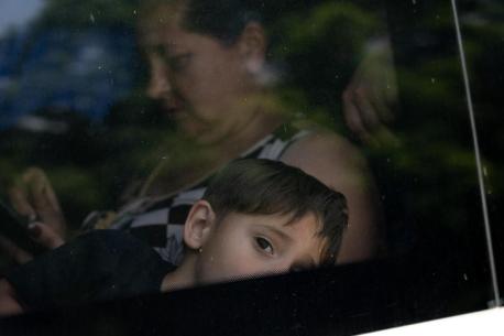 A child and parent evacuating by bus from Kherson, Ukraine, following the dam collapse on June 6, 2023.