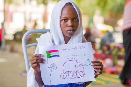 On June 2, 2023, a child displaced by armed conflict in Sudan holds her drawing of a tank.