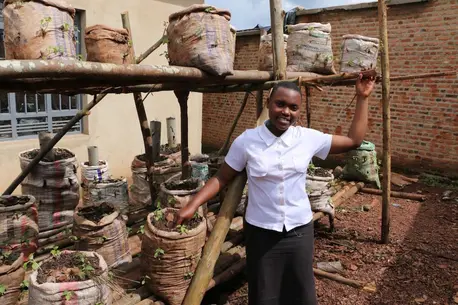 In Burundi, Sandrine, 16, stands with vegetables grown in bags of dirt, part of the Creatables project funded by UNICEF Australia.