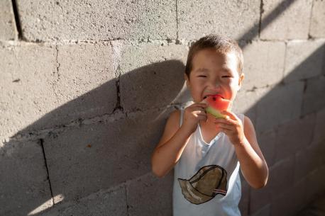 A child eating watermelon outside his home in Kurshab village, Osh Oblast, Kyrgyzstan.
