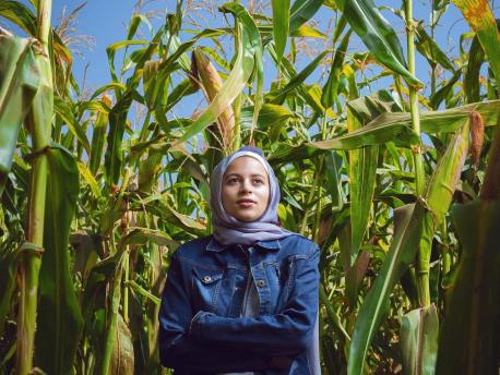 A young woman stands in the middle of a corn field in Egypt.