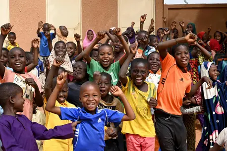 Schoolboys and girls raising their arms and smiling
