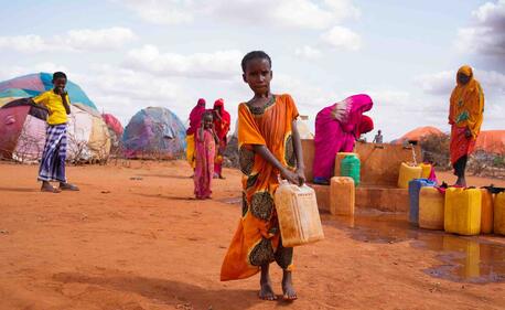 A 10-year-old girl who had to leave her home in Somalia because of drought carries carries water to her home in a temporary settlement.