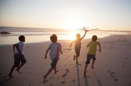 Boys running on the beach at sunset