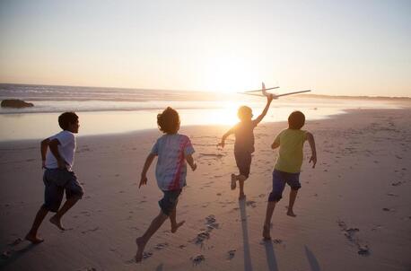 Boys running on the beach at sunset