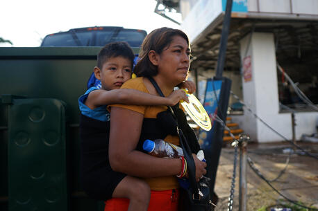 A mother carries her child on her back to make her way through an area of Guerrero state, southwestern Mexico, in wake of Hurricane Otis. Photo by Getty Images.