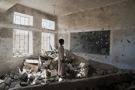 A student stands in the ruins of one of his former classrooms at the Aal Okab school in Saada, Saada Governorate, Yemen.