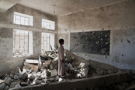 A student stands in the ruins of one of his former classrooms at the Aal Okab school in Saada, Saada Governorate, Yemen.