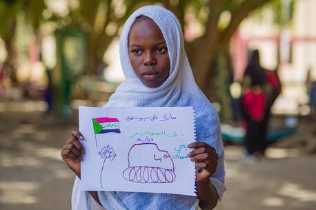 A young girl shows a drawing of a tank representing her experiences with conflict in Sudan at a UNICEF-supported Child-Friendly Space in Madani.