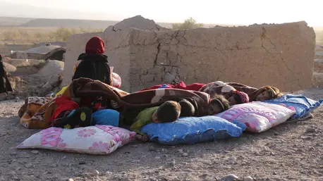 Afghan children rest under a blanket beside damaged houses after earthquake in Sarbuland village of Zendeh Jan district of Herat province on Oct. 7, 2023.