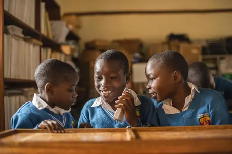 Partially blind students at UNICEF-supported St. Bernadette Primary School in Hoima, Uganda, listen to a recorded lesson from a Victor reader.