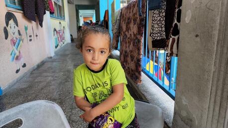 Sileen, 4, is sitting in front of the classrooms at one of the UNRWA school turned into a shelter for many families following the escalation in the Gaza Strip.