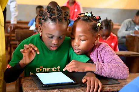 Two schoolgirls look at a tablet screen