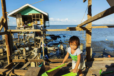 Two-year-old Gwendolyn in Barangay Fatima, Purok 1 in Ubay, Bohol, Philippines, stands among the ruins of her family's home, which was destroyed by a typhoon.