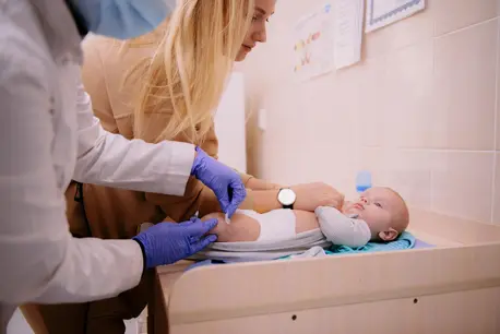 Baby lying down while getting a shot in the leg