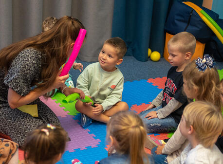 Young children sit on a colorful play mat at a UNICEF-supported Spilno Child Spot in Kharkiv, Ukraine.