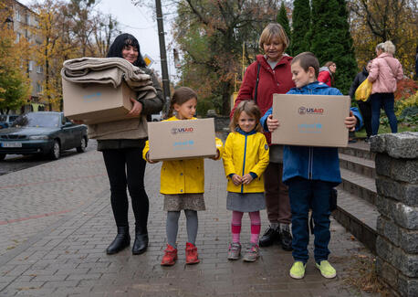 A family in Izium, Kharkivska oblast, Ukraine, carries boxes containing winter clothes distributed by UNICEF.