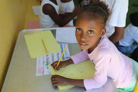 Seven-year-old Lovenska of Haiti works on a drawing at a UNICEF-supported child-friendly space in Delmas 6, downtown Port-au-Prince.