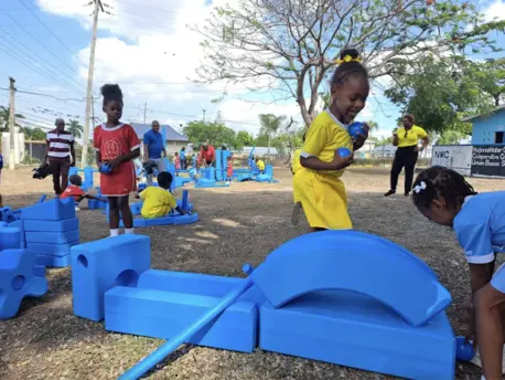 Children from National Water Commission Credit Union Basic School playing with blue blocks at the pop-up playground supported by UNICEF.