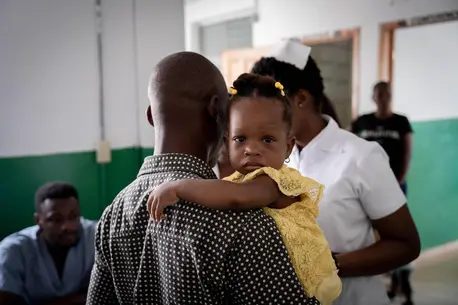 A child hugs her father in the vaccination ward of the Justinien hospital in Cap-Haitien.