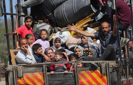Children with their families sitting in the back of a truck during their displacement from areas witnessing an escalation in hostilities in Rafah, south of the Gaza Strip.