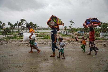 Parents and children head to a shelter ahead of Cyclone Remal's landfall in Bangladesh on May 26.