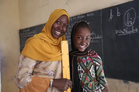  A UNICEF-supported teacher and one of her students stand in front of the chalkboard at a school in Mali.