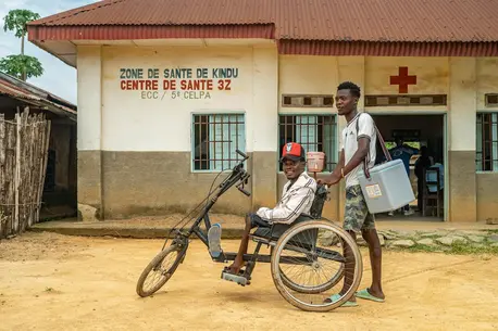 From left: Rajabu Vambise, 27, polio survivor and UNICEF-supported community worker, with a vaccinator during a polio vaccination campaign in Kindu, Maniema province, Democratic Republic of the Congo, on March 30, 2024.