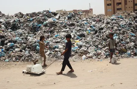 Children pass through a waste dump while searching for clean,safe drinking water in Rafah, southern Gaza Strip.