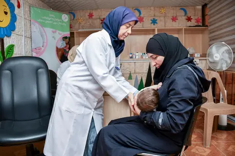 A pediatrician shows a mother a breastfeeding position at a UNICEF-supported health and nutrition center in Harasta, Rural Damascus, Syria.