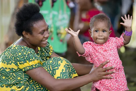 A mother and daughter smile in Papua New Guinea. The little girl is waiting to be seen by medical professionals.