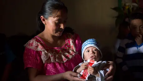 Mother feeding child a RUTF packet